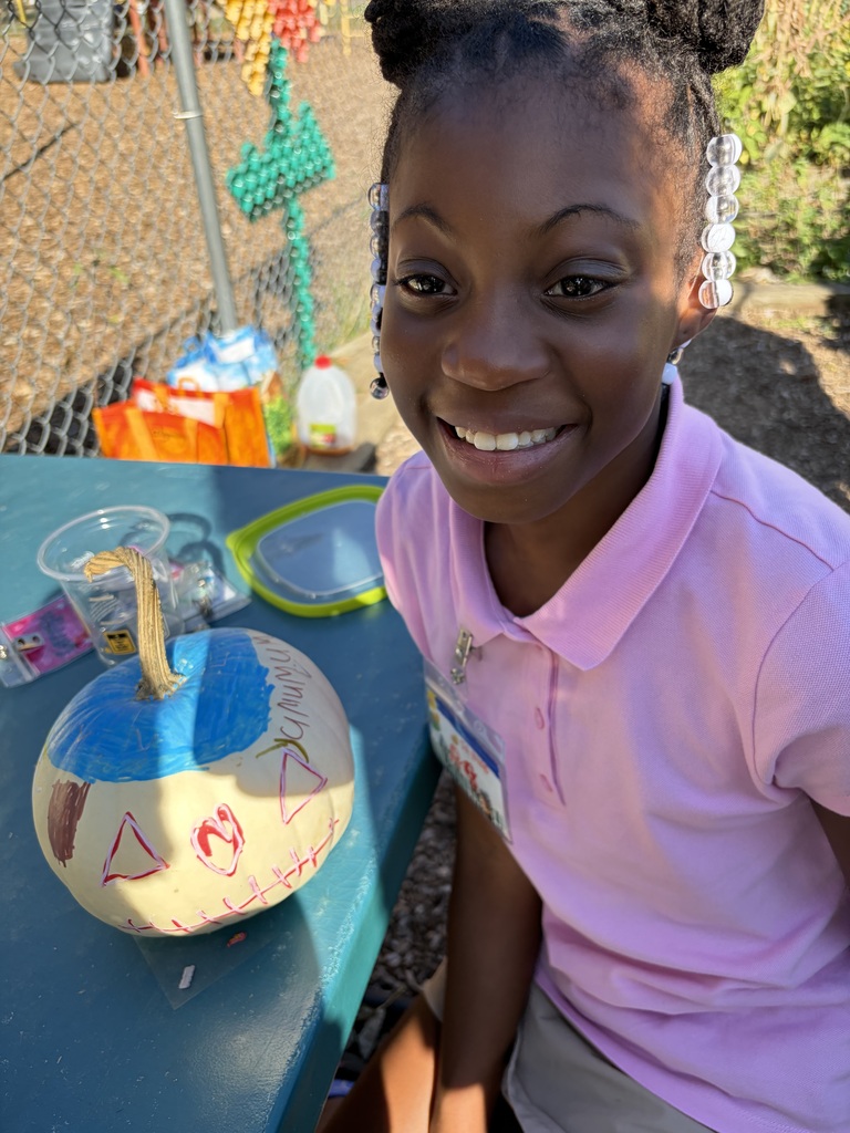 Student smiling with their painted pumpkin.