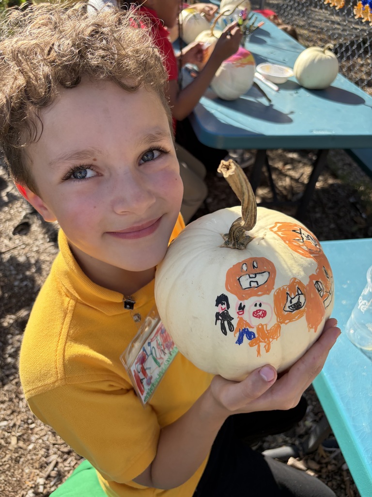 Student smiling with their painted pumpkin.