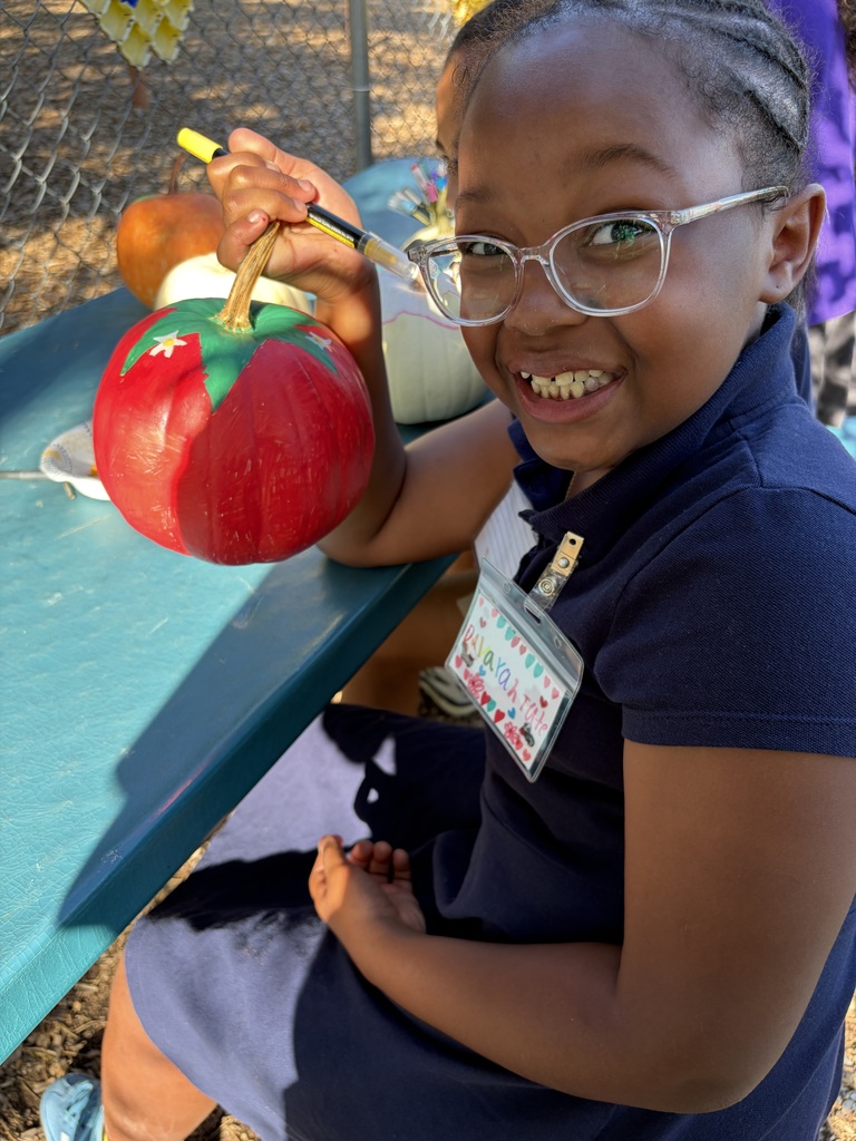 Student smiling with their painted pumpkin.