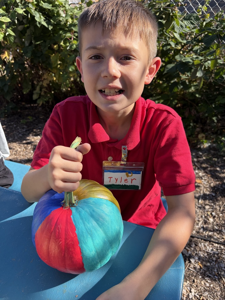 Student smiling with their painted pumpkin.