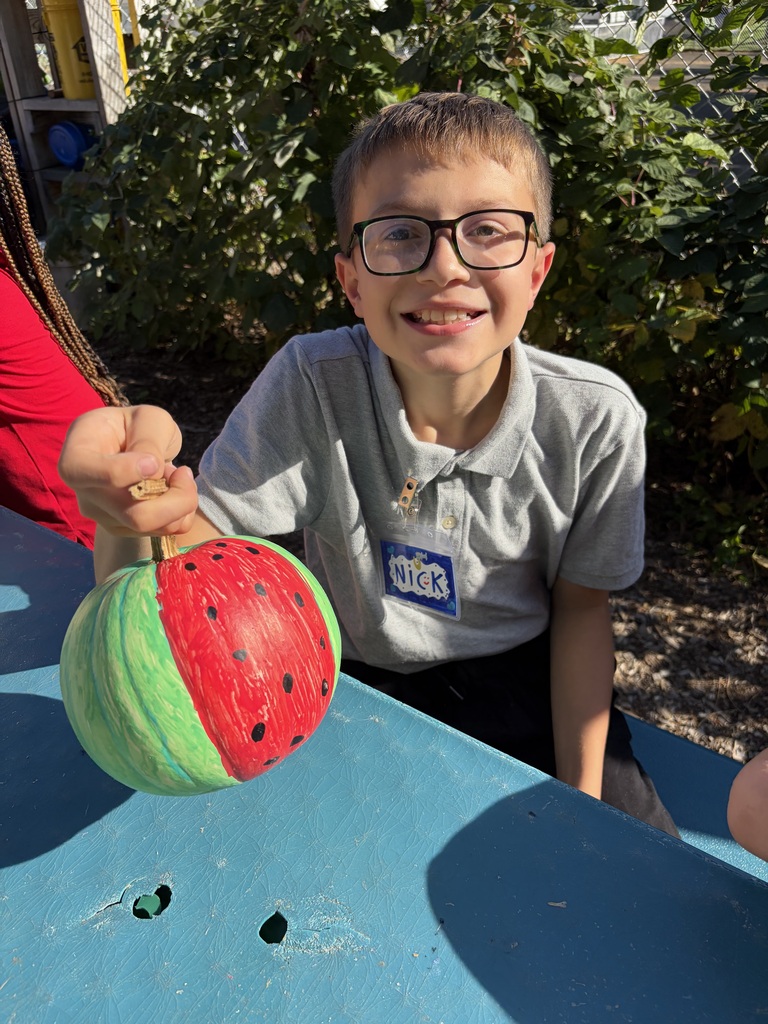 Student smiling with their painted pumpkin.