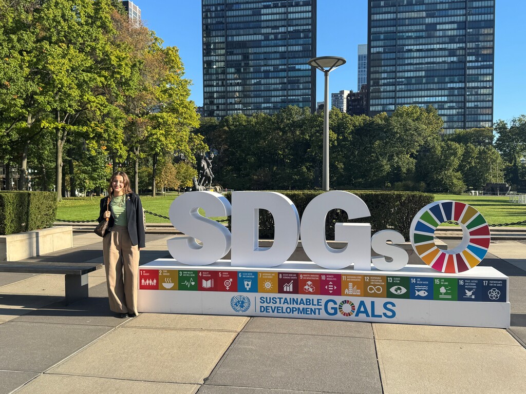 Theofania Nacopoulos stands in front of the Sustainable Development Goals sign outside the UN building