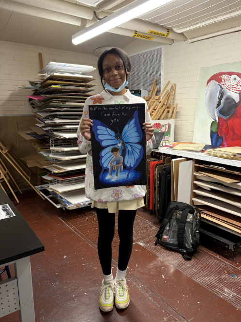A student holding up her art that shows a kid sitting in front of a Blue butterfly that is giving him a white heart from behind.