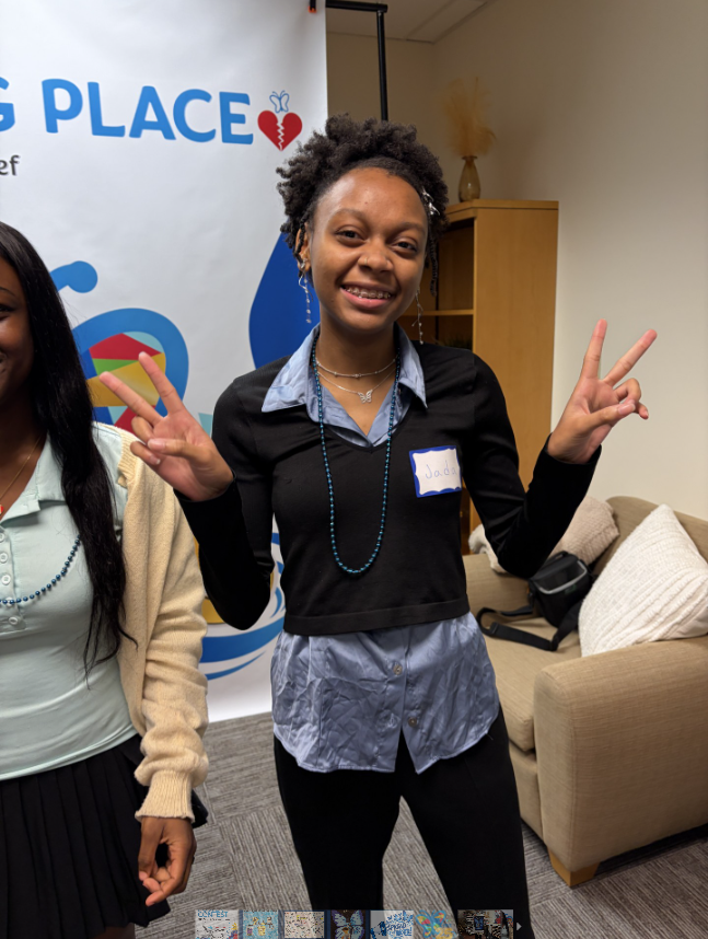 A young girl smiling and holding up peace signs.