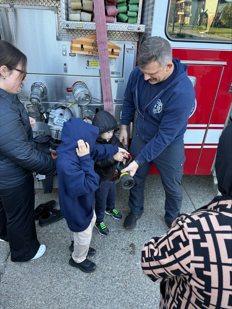 Firefighter showing students the hose on the firetruck