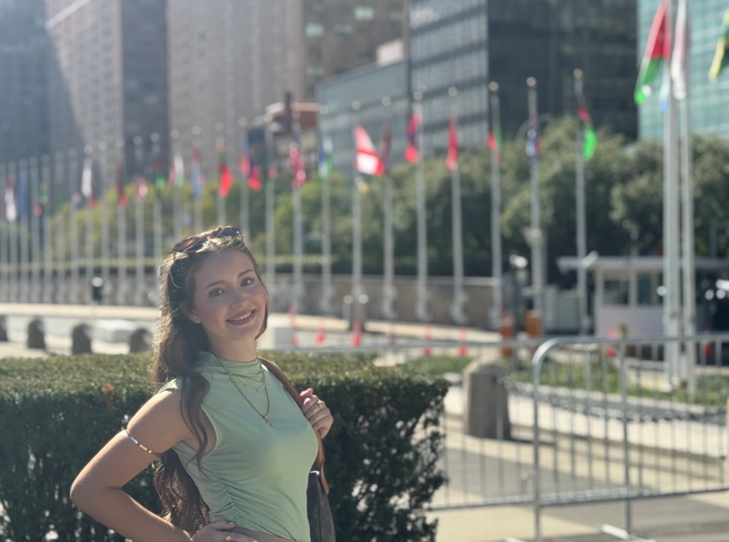 Theofania Nacopoulos standing outside and there are different country flags in the back.