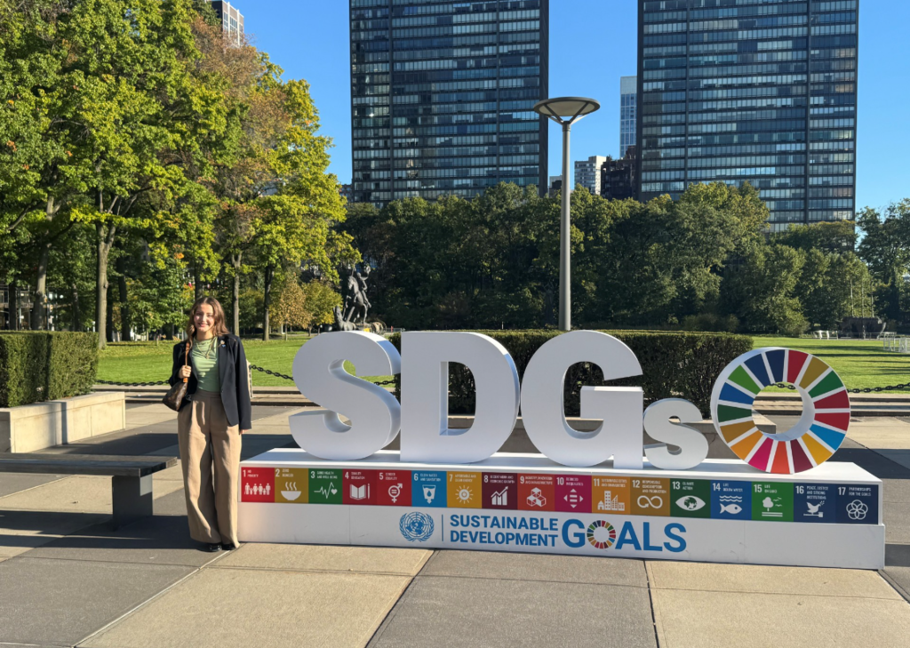 Theofania Nacopoulos standing outside and next to the Sustainable Development Goals Sign.