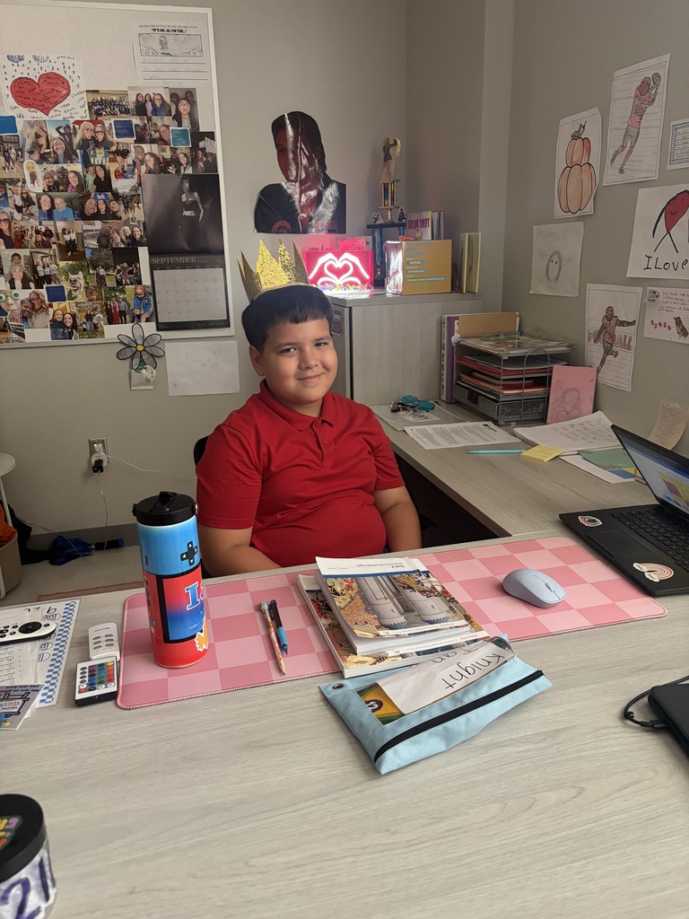 Male student sitting at the teacher's desk.