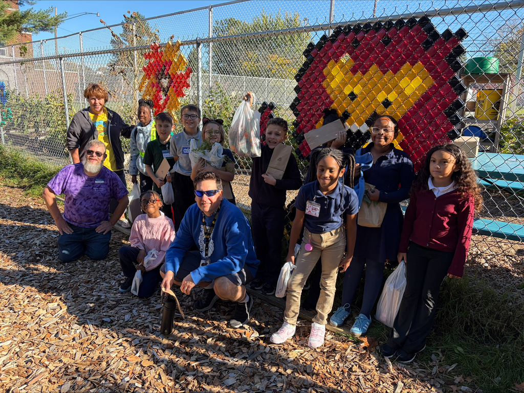 Students and Garden Club staff posing for a picture in front of the garden fence with the Lincoln Lion on it.