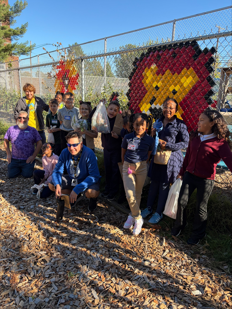 Students and Garden Club staff posing for a picture in front of the garden fence with the Lincoln Lion on it.
