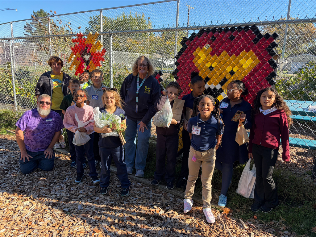 Students and Garden Club staff posing for a picture in front of the garden fence with the Lincoln Lion on it.