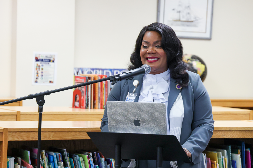 Superintend/ CEO Dr. Natalyn Gibbs smiling while giving a speech at the podium.
