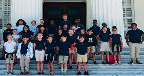 AC Moore Primary School students smiling on steps in front of a building