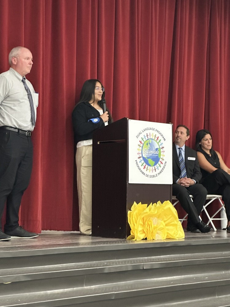 A student speaks at a podium , pictured with EUSD staff.