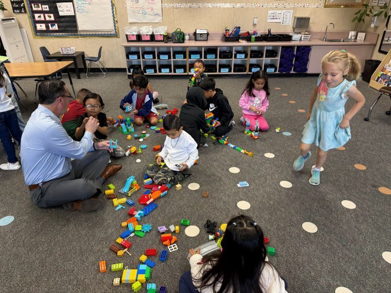 Kindergarten students play with LEGOS with guidance from the Superintendent.