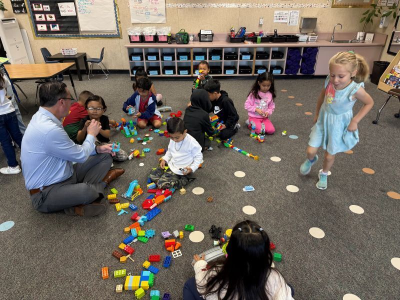 Kindergarten students play with LEGOS with guidance from the Superintendent.