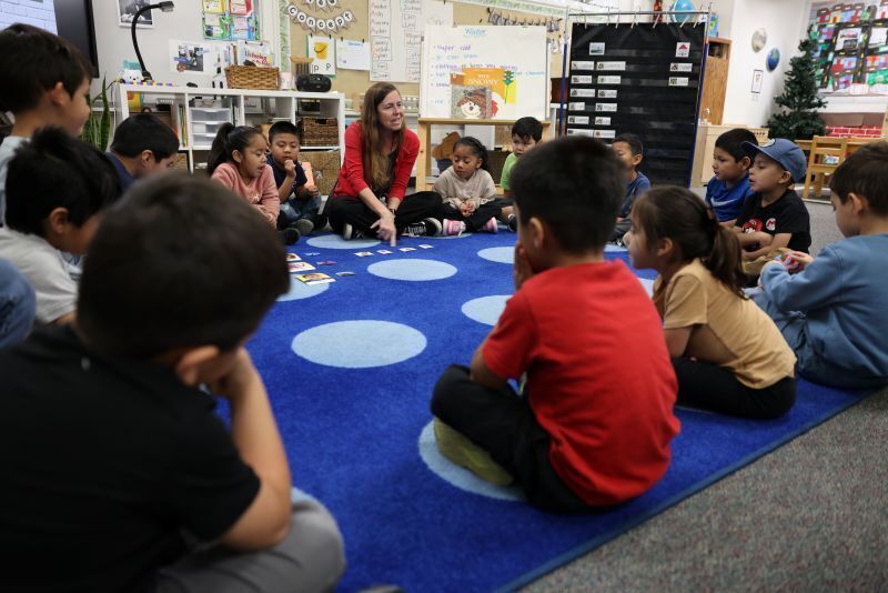 A classroom of Transitional Kindergarten students sit on the carpet with their teacher.