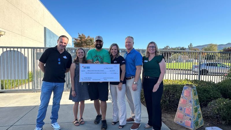 Reidy Creek Physical Education Teacher Simon Vieaux receives a large check from the American Heart Association. El profesor de educación física de Reidy Creek, Simon Vieaux, recibe un gran cheque de la Asociación Estadounidense del Corazón.