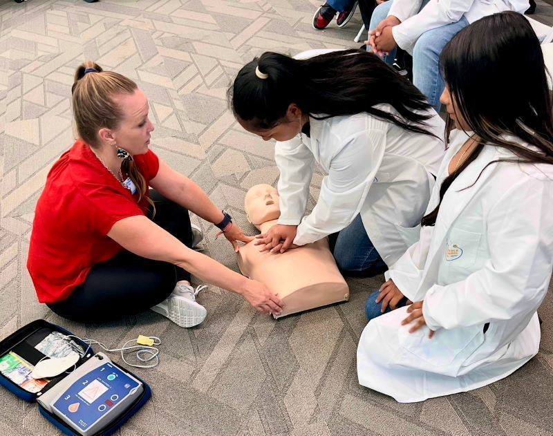 A student performs CPR on a dummy.  Una estudiante realiza RCP en un maniquí.