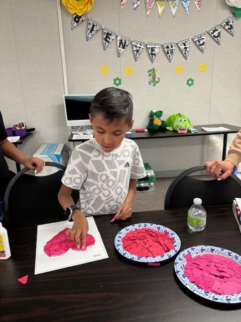 Student Liam Sanchez Villegas completes his heart collage project.