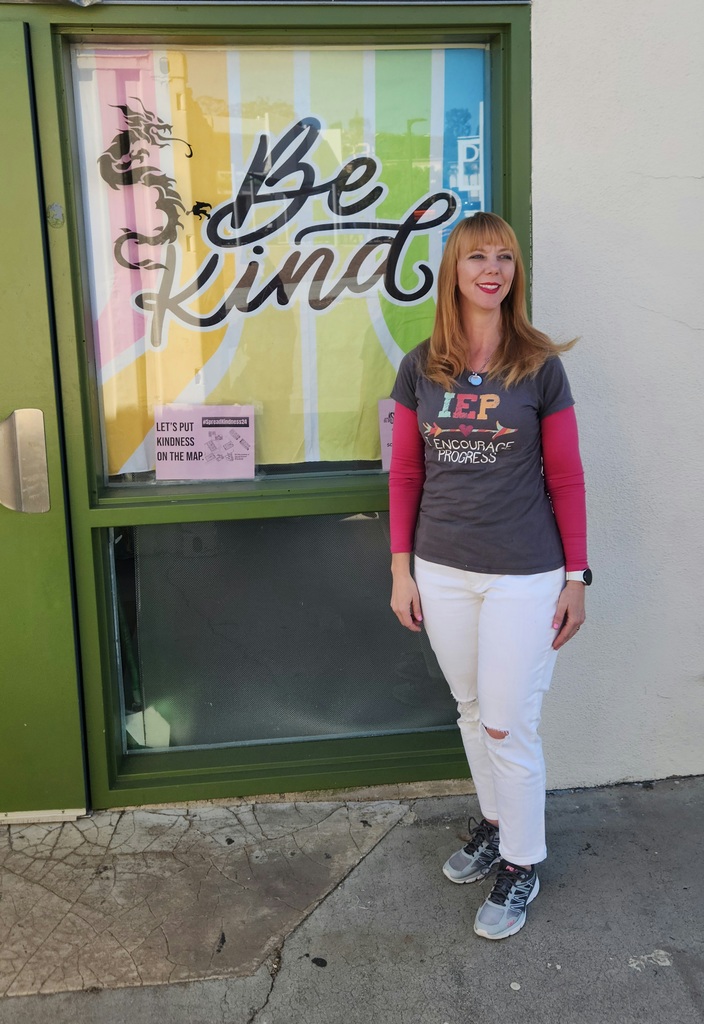 Mrs. Chandler standing behind a sign that says, "Be Kind "and "Lets Put Kindness on the Map"
