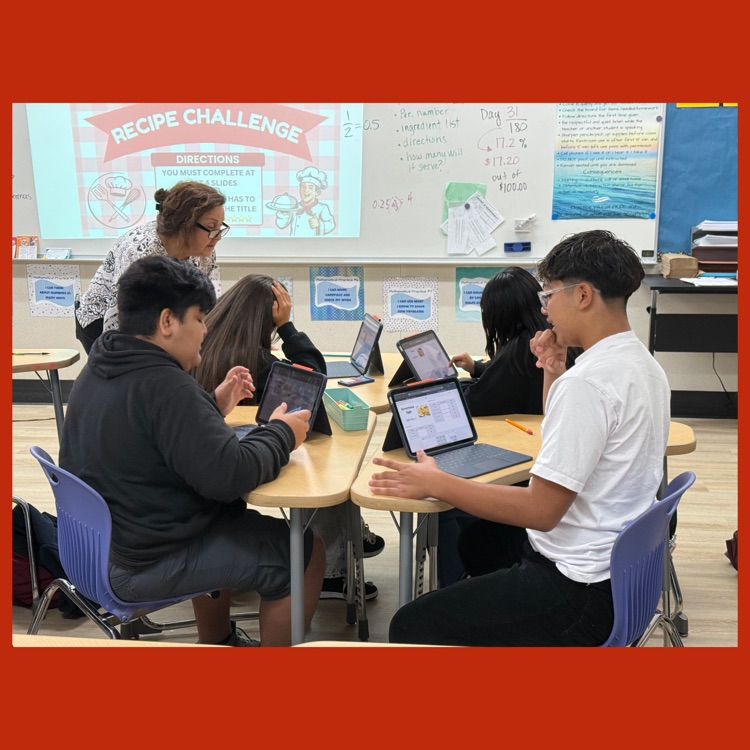 A photo of Mrs. Sisson helping a group of students scale recipes in the "Recipe Challenge"