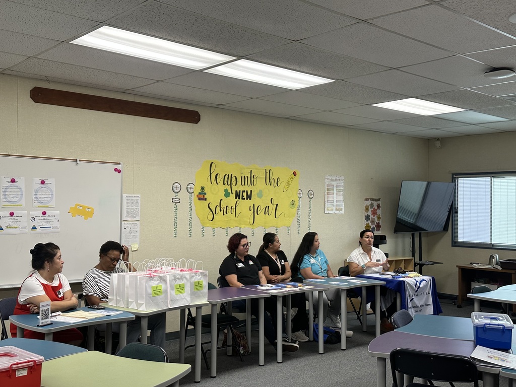Community Partners seated at a table sharing resources with families. 