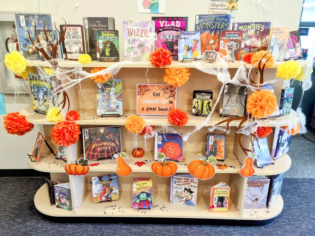 Library entrance display of spooky books surrounded by Marigold flowers