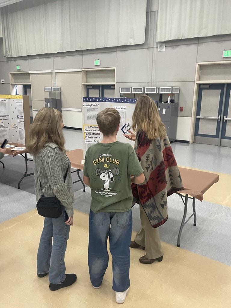 students standing with parent and teacher in front of display board