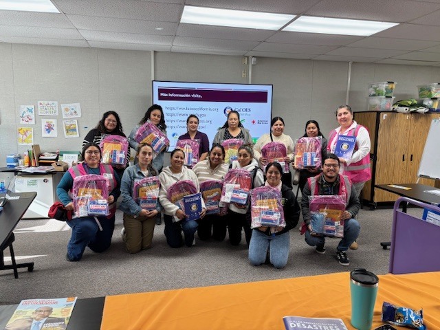 Nine parents, three Universidad Popular community educators, and Glen View's Family Liaison pose for a picture together after having received free disaster preparedness backpack starter kits