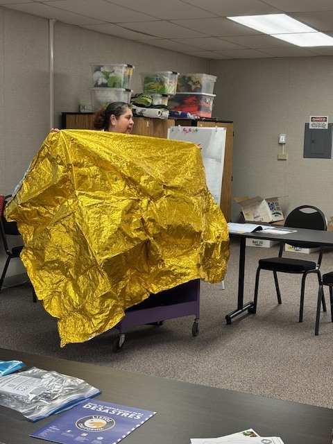 Community educator Vanessa Sifuentes shows parents how an emergency thermal blanket looks like