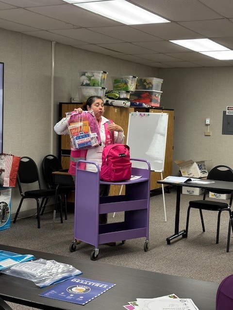 Community educator Vanessa Sifuentes shows and explains to parents what a disaster preparedness backpack is while lifting up a backpack