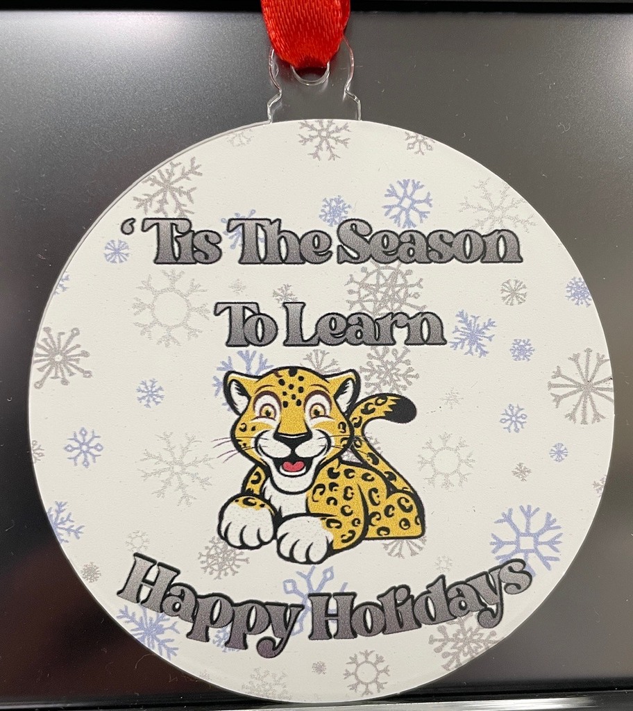 Circular ornament with snowflakes and a cartoon jaguar, with the text "'Tis The Season To Learn Happy Holidays."