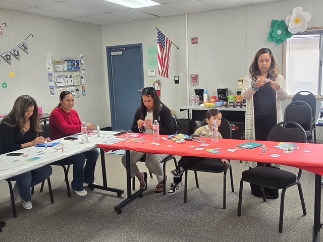 Three moms a child and Ms. Christine Carrera work on their self care goodie bags while sitting in a u shaped table. 