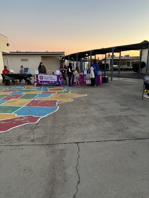 Two parents and a child browse the many resources offered by community partners such as the escondido Public Library, Universidad Popular, and Kelly Rutherford and Waltanna Khommarath