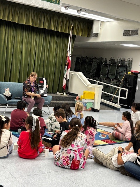 Escondido Public Librarian Mrs. Garcia holds a book while reading to 13 children inside the multipurpose rrom.