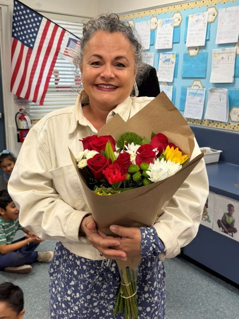 Teacher holding flowers with a big smile on her face