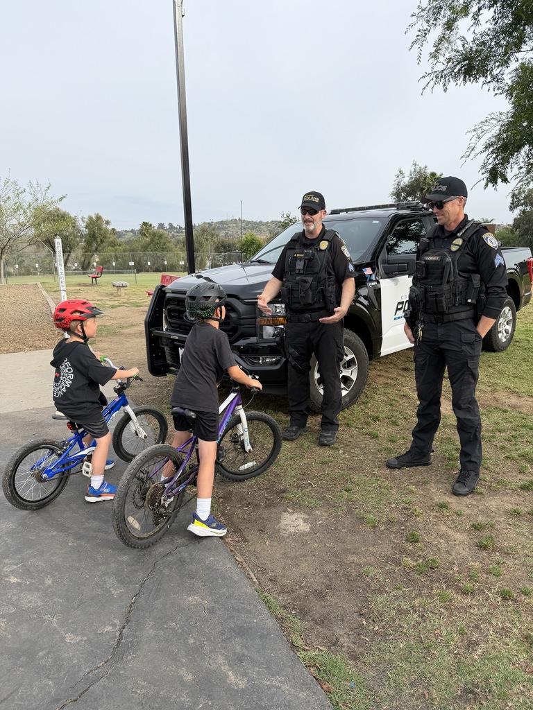 2 students with 2 police officers and a police car in the back