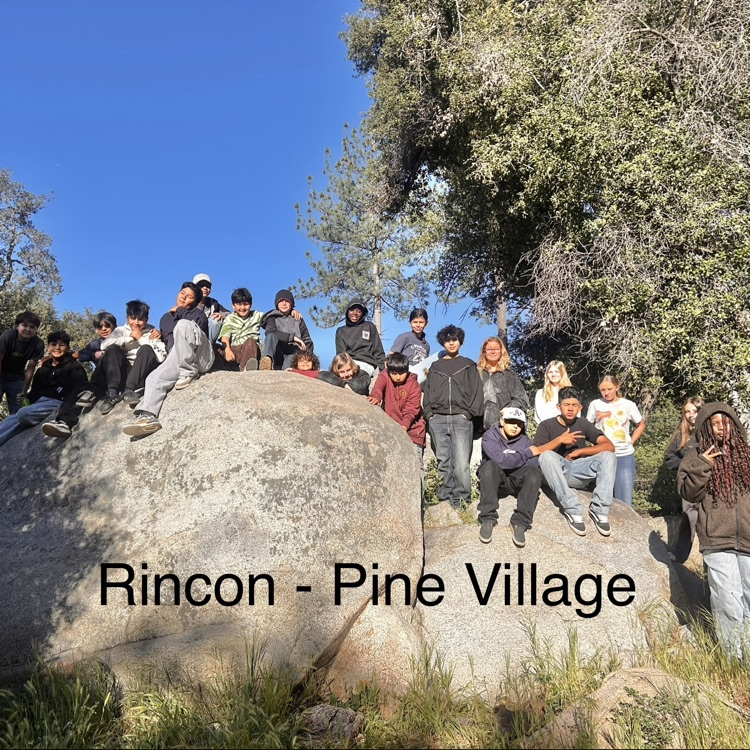 Rincon students at 6th grade camp sitting together on a rock. 