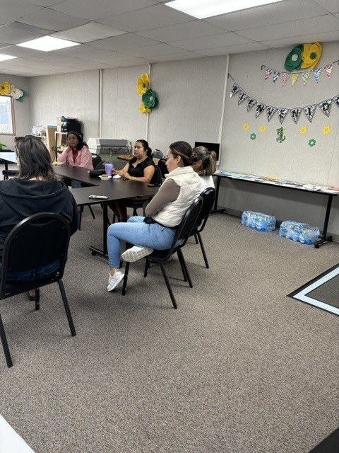 Six parents are sitting inside room 21 while listening to Principal Lopez's Coffee with the Principal message. 