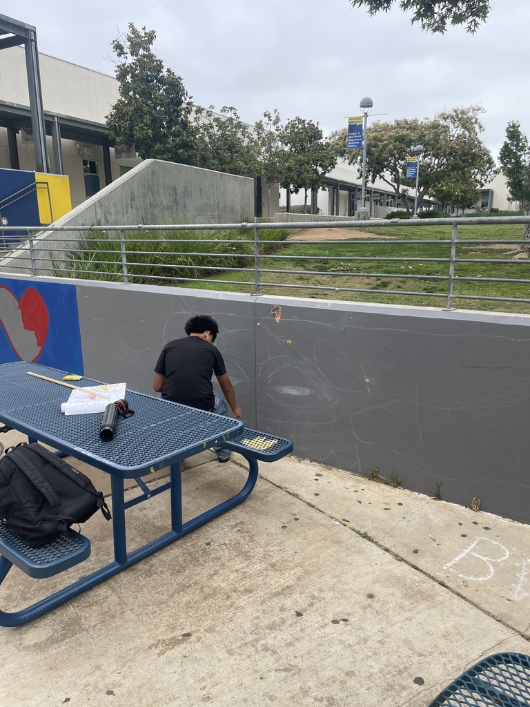 Student preping artwork on wall