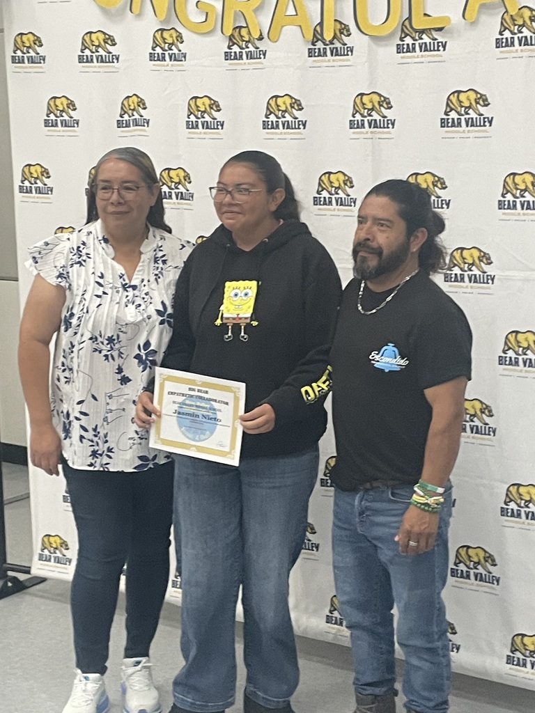 student holding award with parents