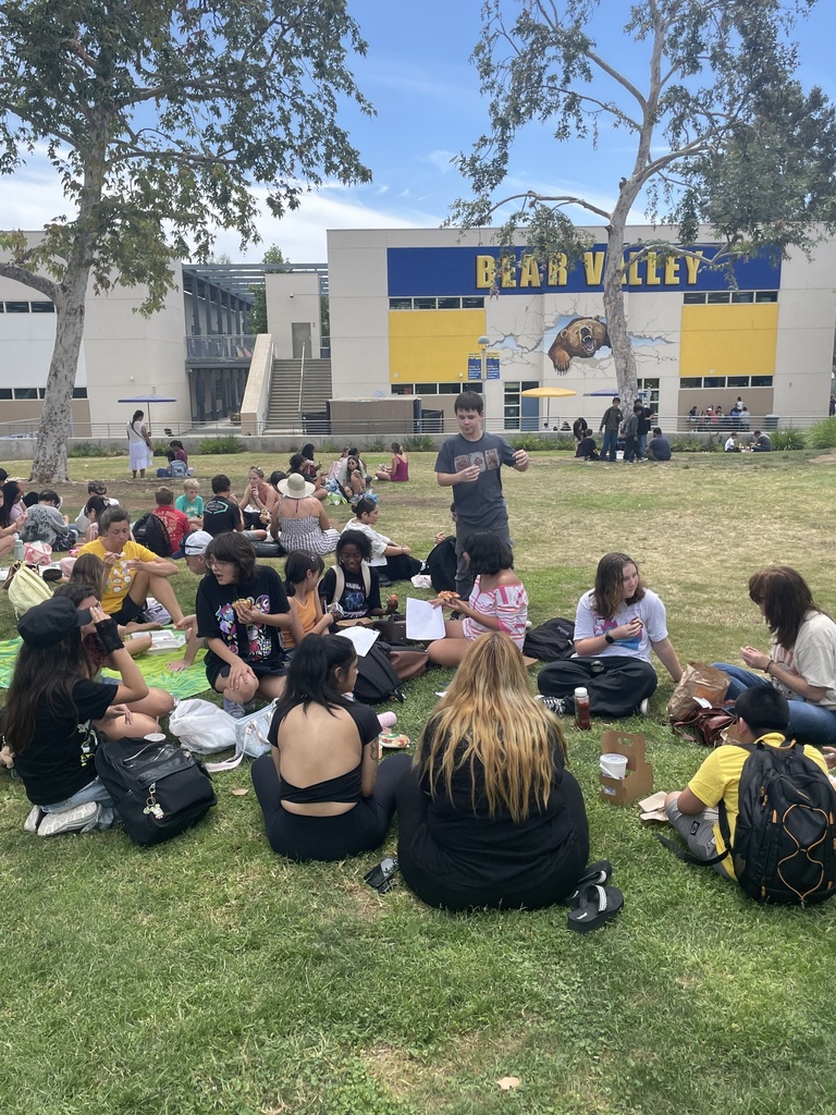 students eating lunch with their families on the grass