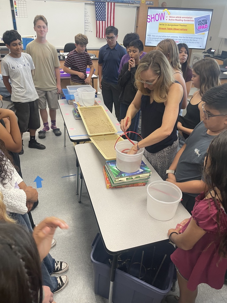 Students working with a model of sand and water, teacher doing the steps for the students