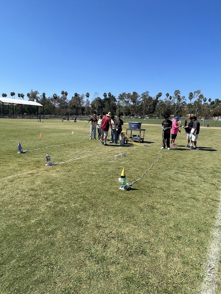 Students preparing to launch their rocket on the field