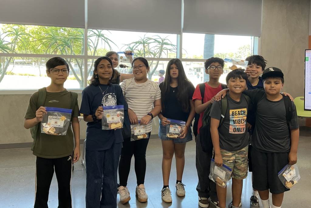 Nine smiling students holding a bag of cookies. 