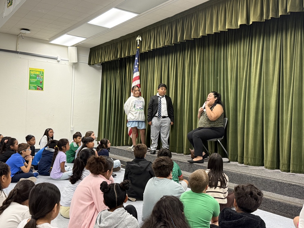 Council woman on the right side wearing green and two students to her right on a stage 