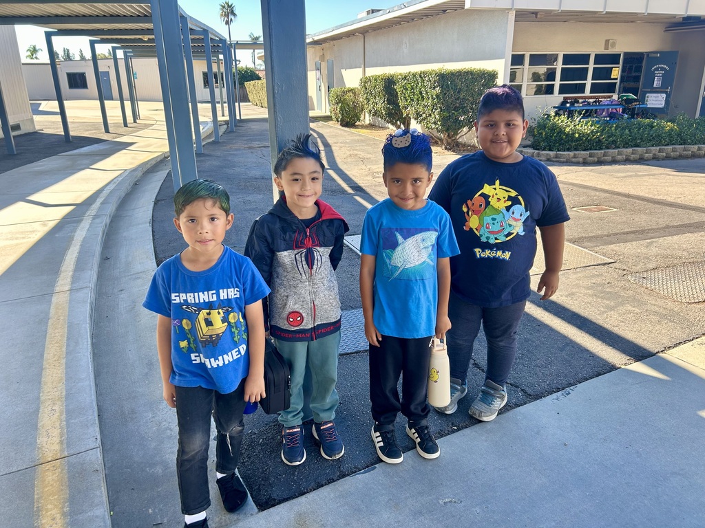 four boy students with crazy hair (blue) and blue attire  