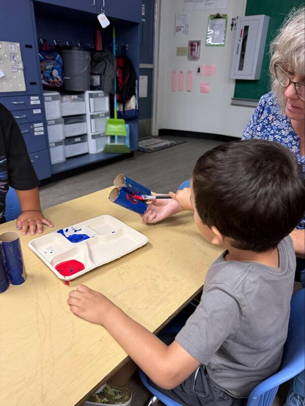 A Transitional Kindergarten student paints with his teacher.