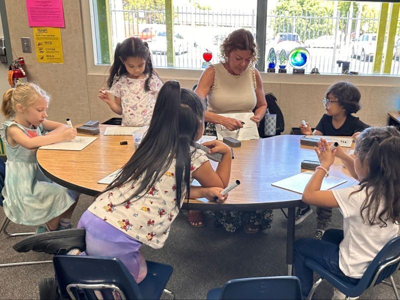 Kindergarten students learn math in a small group with their teacher.